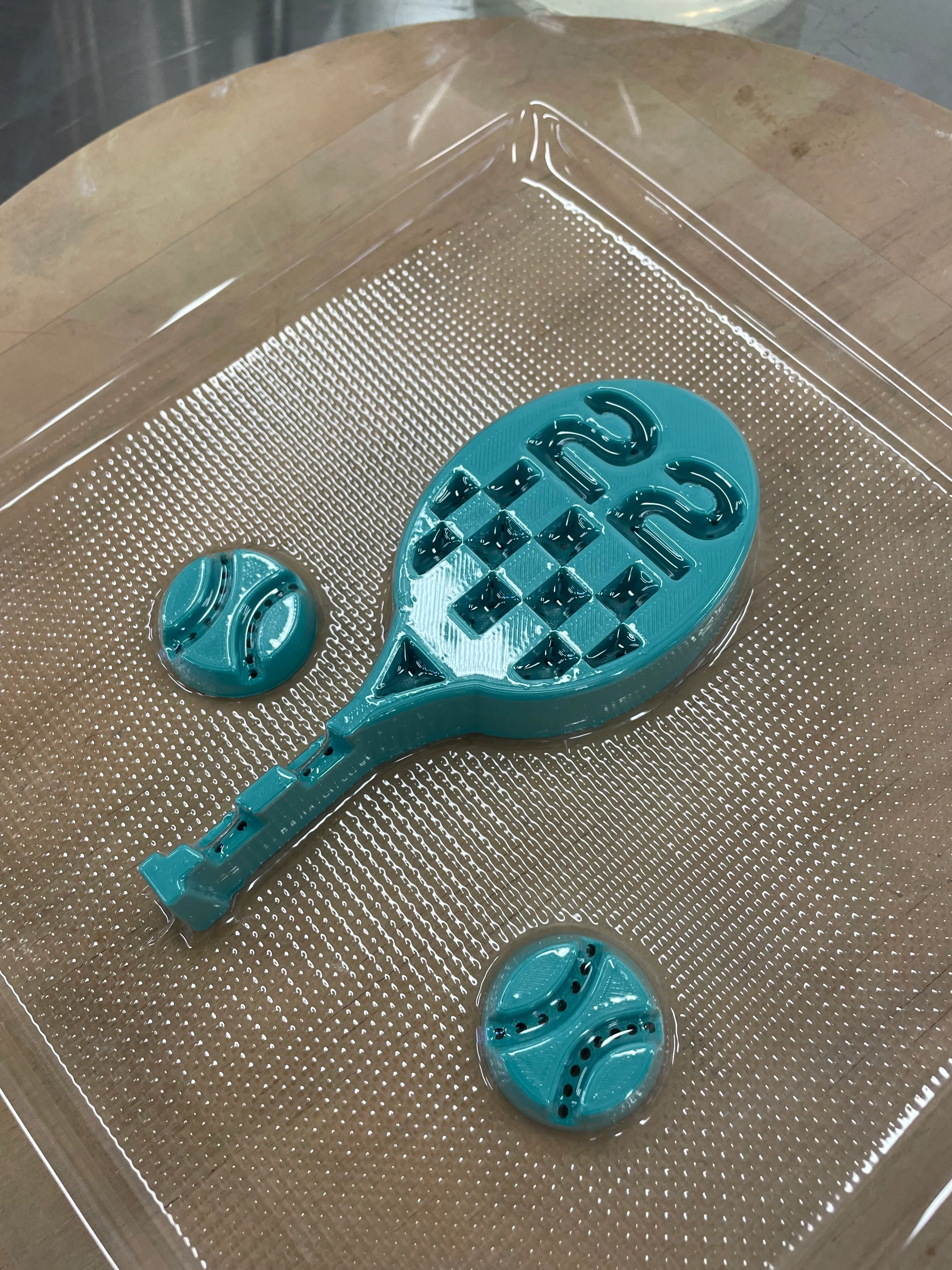 A 3D-printed PLA positive on the vacuum-former, with a heated plastic sheet drawn tight over the form.