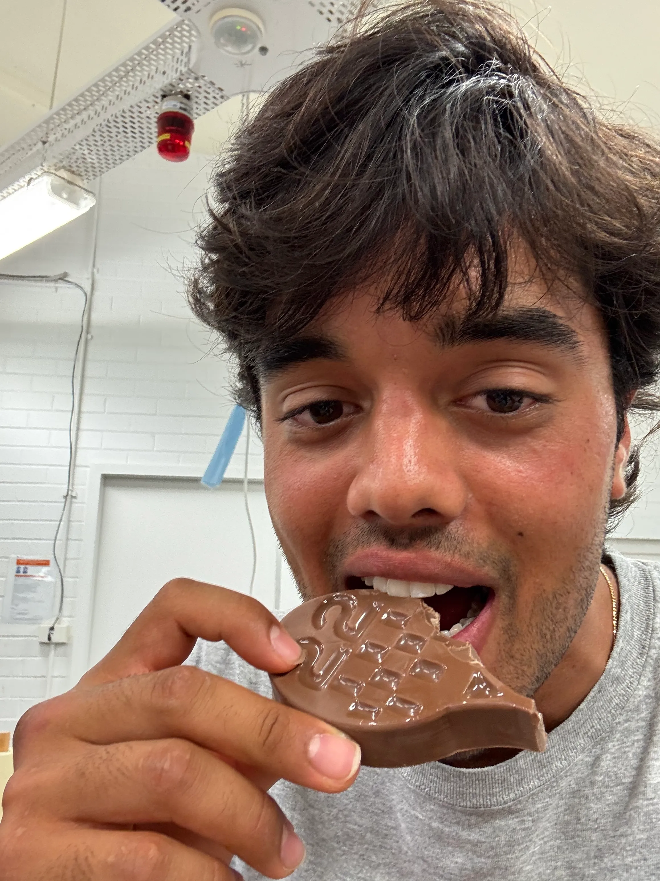 Tal Cohen in the DECO2018 workshop, taking the first bite from the chocolate tennis racquet — the bite mark visible at the rim.